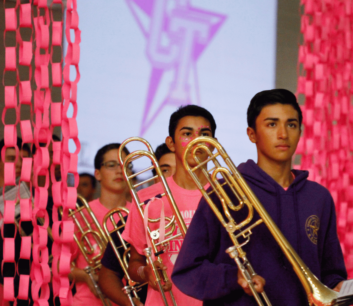 Robert Molina leads trombones into gym for pink out pep rally.