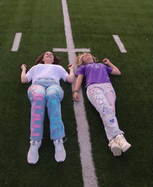 Seniors Rylee Karber, left, and Evelyn Jackson lay on the astroturf and watch the sun rise on the practice field during Senior Sunrise.