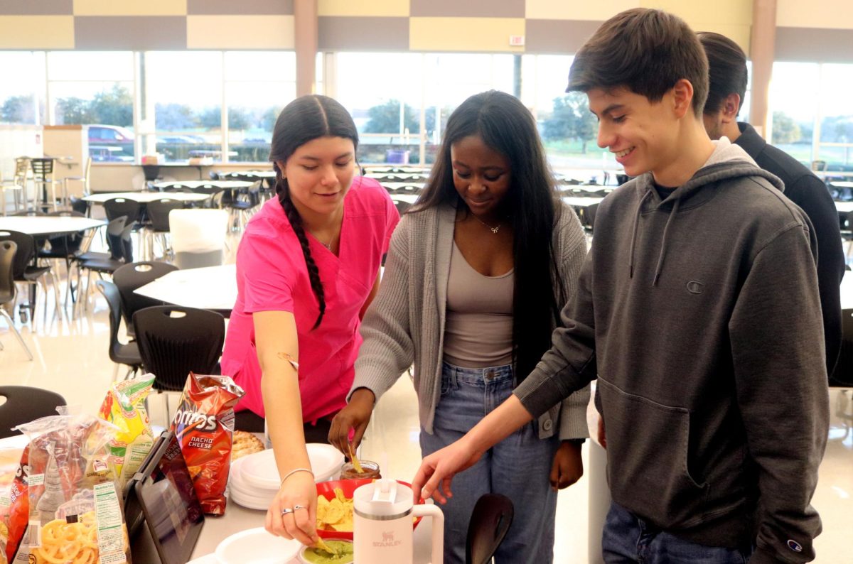 GRADE NAME NAME, senior Perfect Kyanga and GRADE NAME NAME help themselves to chips, salsa and guacamole at the American/Mexican Table