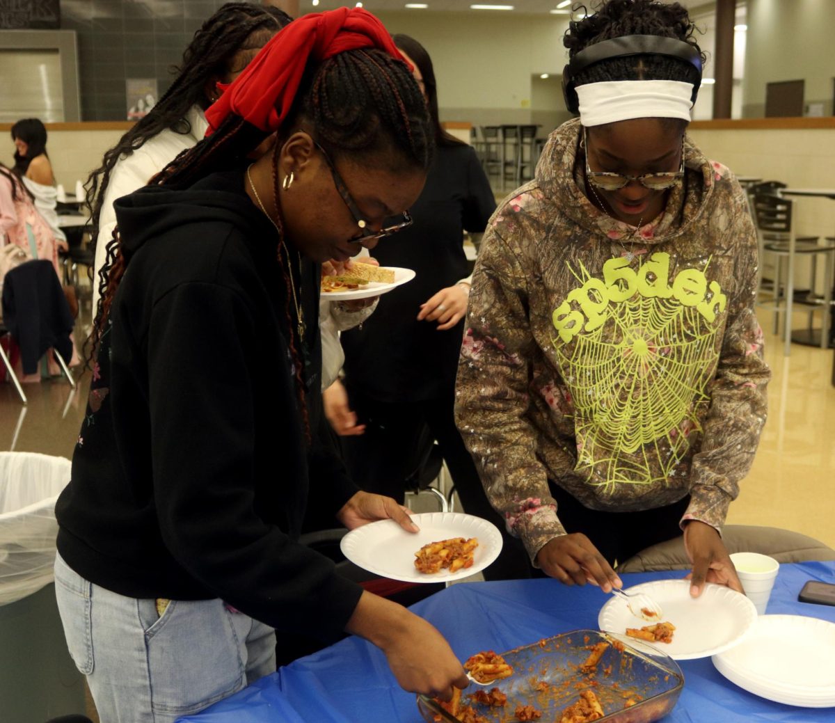 GRADE Precious Nkenyero and GRADE Kyanga serve themselves pasta from the Italy table. 